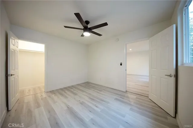 an empty room with wooden floor a ceiling fan and windows