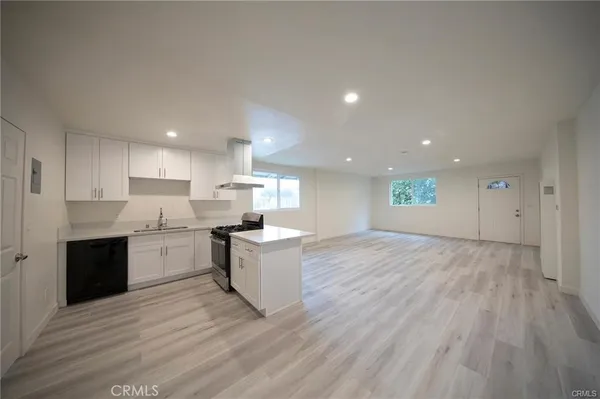 a large kitchen with kitchen island a sink dishwasher a stove and a refrigerator with wooden floor