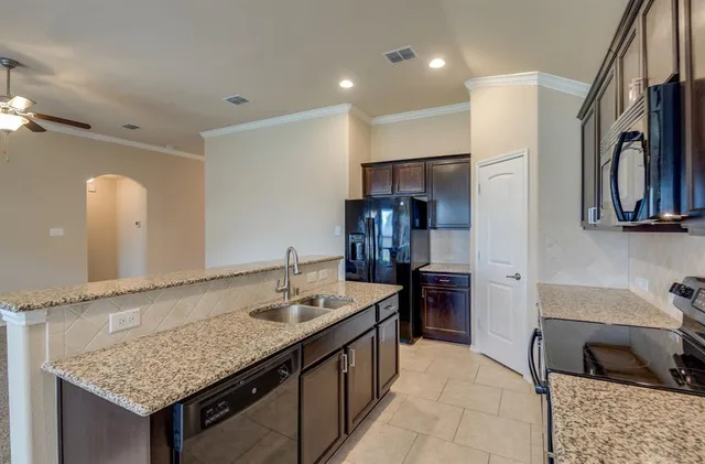a kitchen with stainless steel appliances granite countertop a sink a stove and a refrigerator
