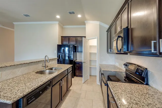 a kitchen with granite countertop a sink stainless steel appliances and cabinets