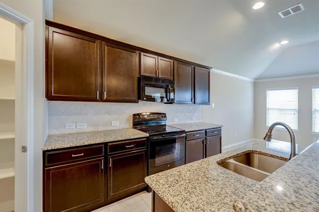 a kitchen with granite countertop a sink and a stove top oven