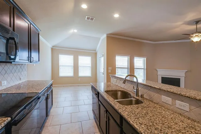 a view of living room kitchen with granite countertop stainless steel appliances stove sink and refrigerator