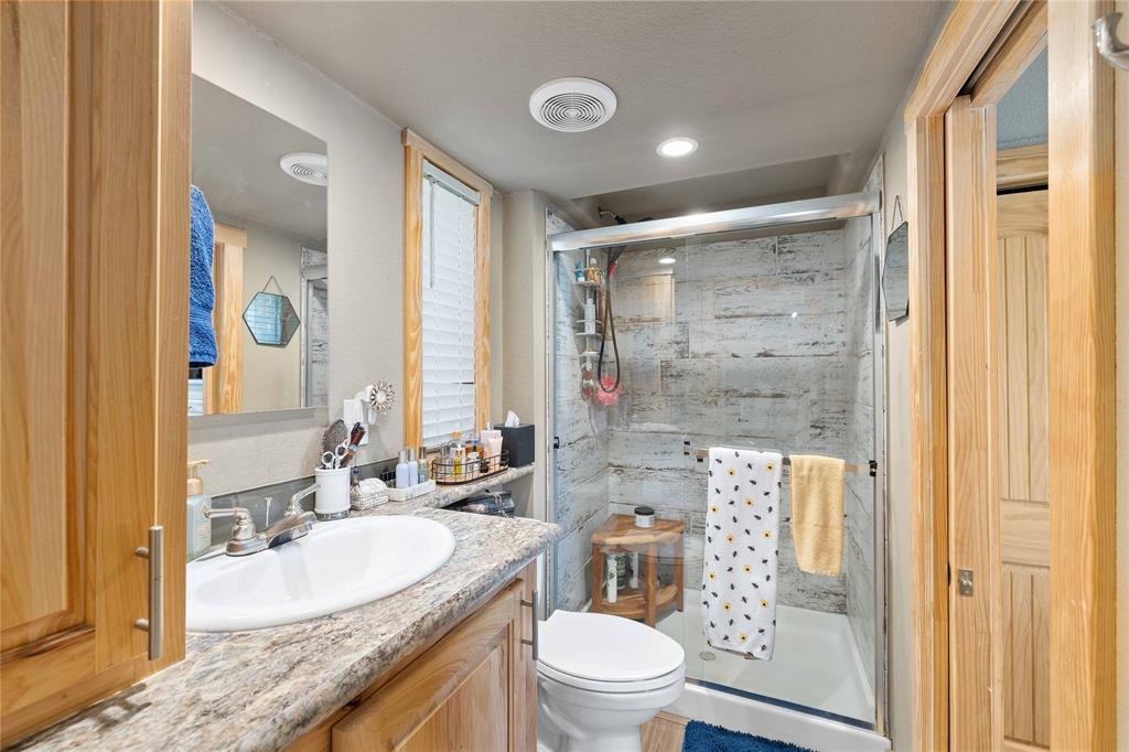 1010 Fm 583 Street West Rising Star, TX 76471 - Photo 38 of 40 a bathroom with a granite countertop sink a mirror a toilet and shower