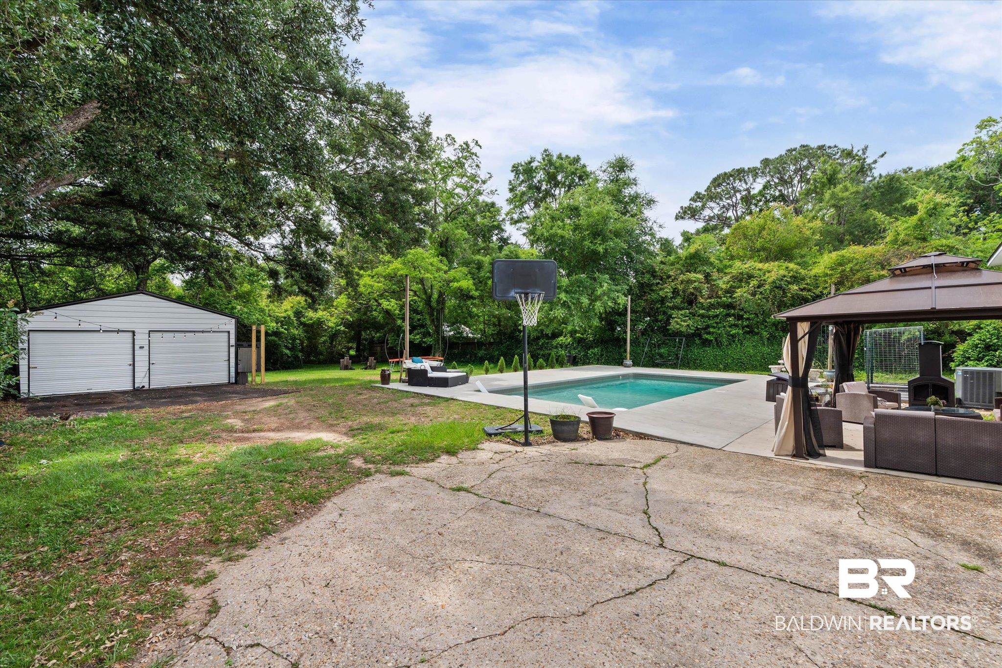 4213 Shan Drive East Mobile, AL 36693 - Photo 25 of 35 Expansive outdoor area featuring a swimming pool, concrete patio, and a separate two-car garage