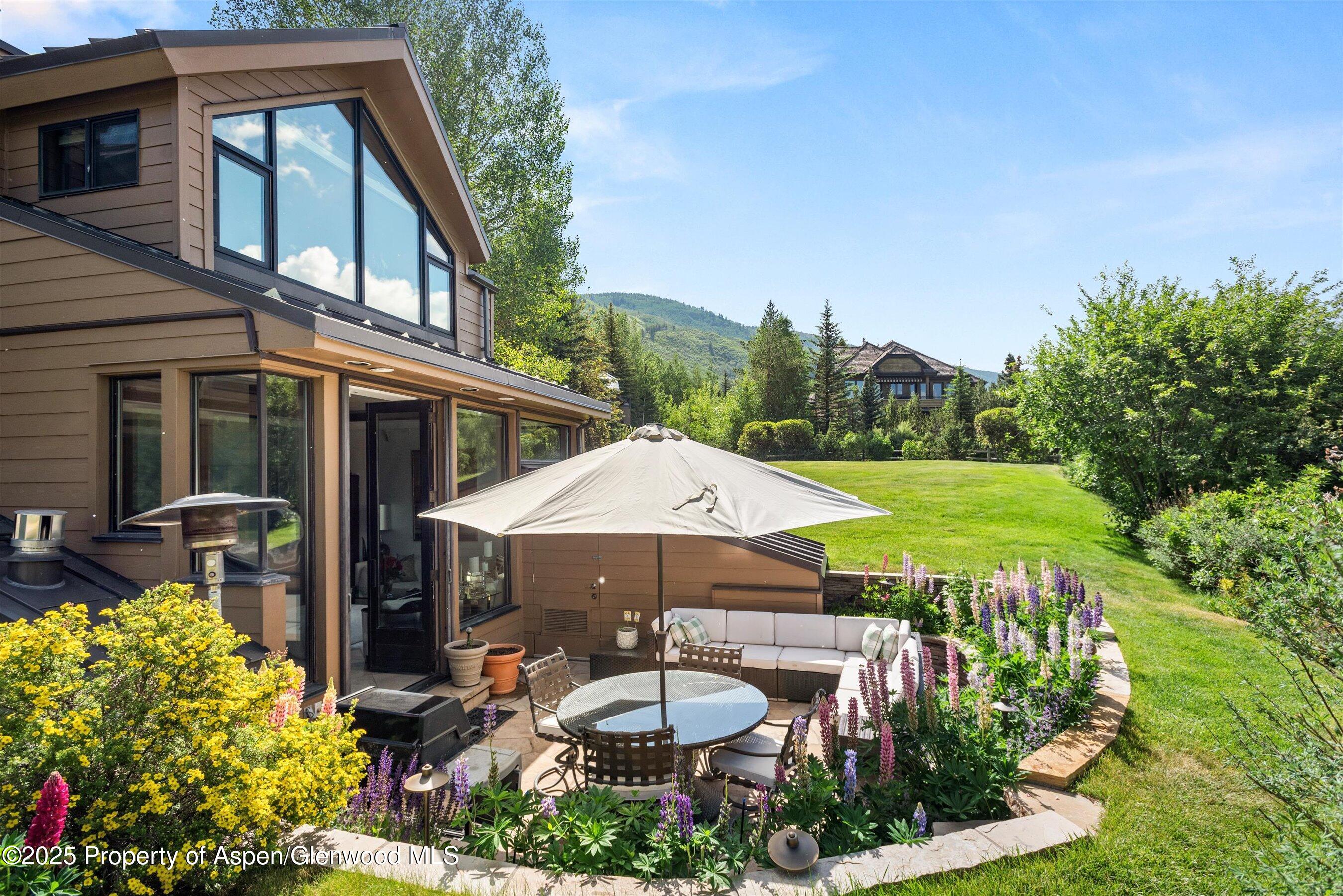 155 Lone Pine Road, Unit 9 Aspen, CO 81611 - Photo 23 of 27 a patio with a table and chairs under an umbrella