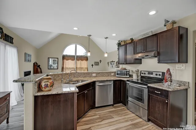 a kitchen with stainless steel appliances granite countertop a stove a sink dishwasher and a microwave oven with large cabinets