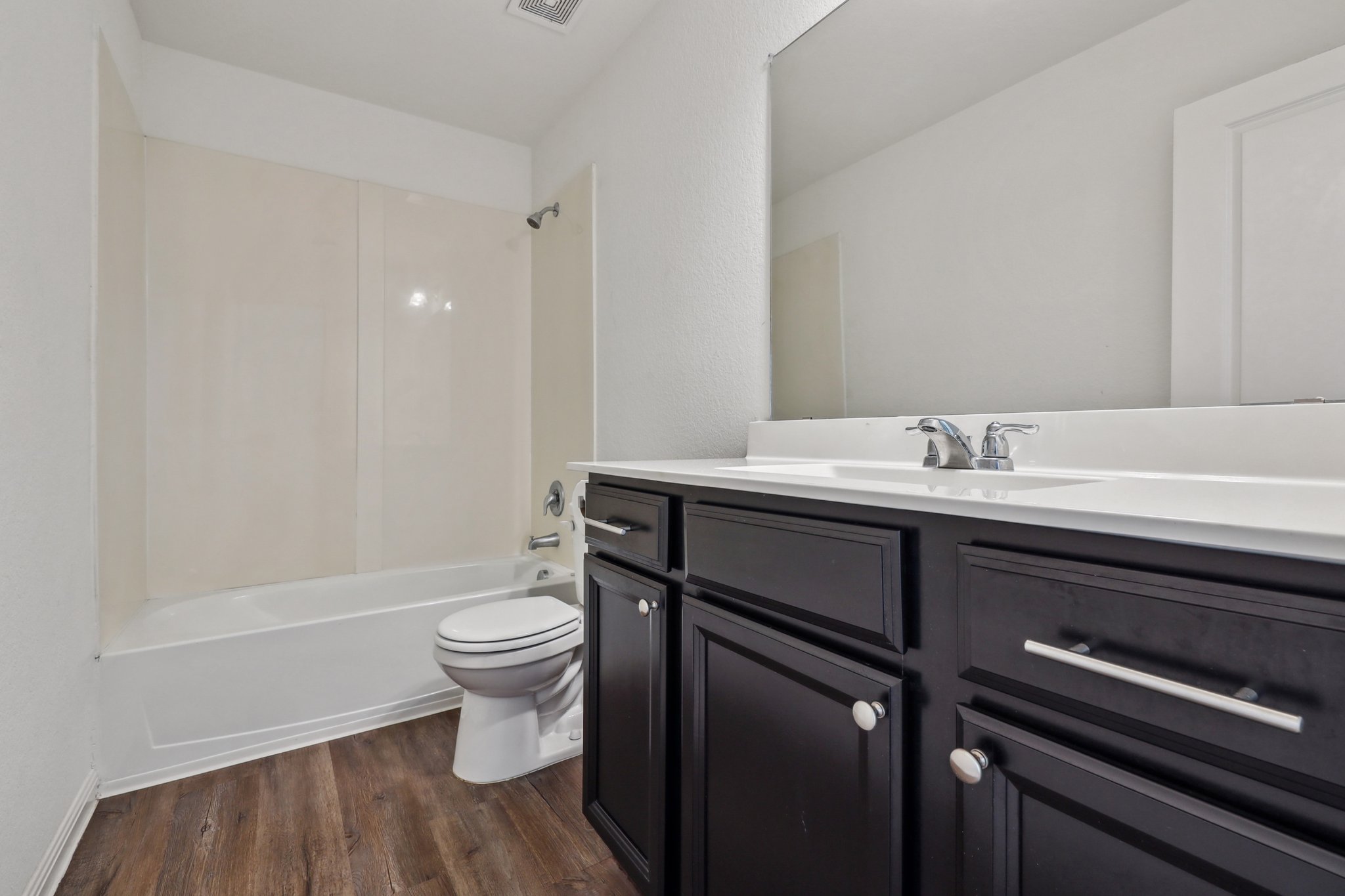 14105 Jeannette Rankin Rd Manor Manor, TX 78653 - Photo 14 of 29 Bathroom with vanity, dark wood-type flooring, washtub / shower combination.