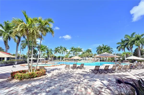 a view of a swimming pool with a lounge chair and palm trees