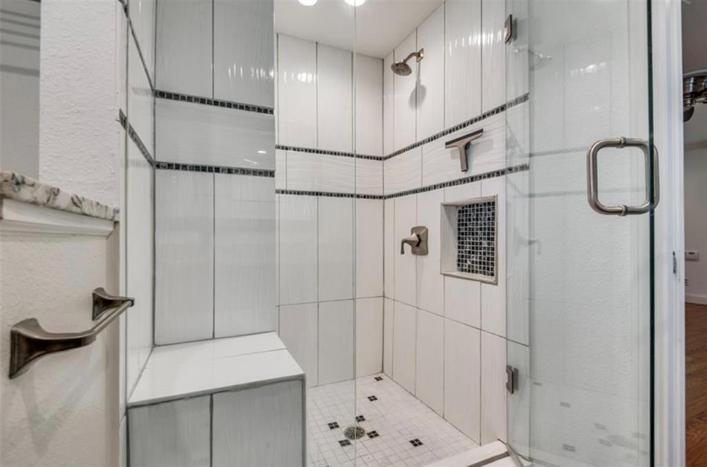 13038 Copenhill Road Dallas, TX 75240 - Photo 9 of 15 Glass-enclosed shower with white tiled walls, mosaic accent band, built-in bench, recessed shelf with mosaic tile, and brushed nickel fixtures