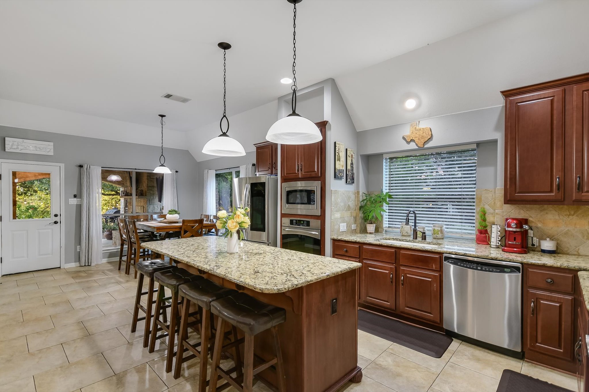 300 Wesley Ridge Drive Spicewood, TX 78669 - Photo 13 of 40 a kitchen with a stove a kitchen island a sink dining table and chairs