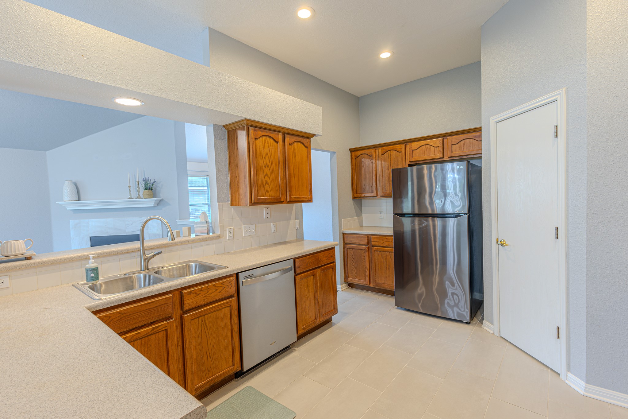 208 Discovery Kyle, TX 78640 - Photo 13 of 31 Kitchen featuring wood cabinetry, stainless steel appliances, a double basin sink, light-toned countertops, and tile flooring