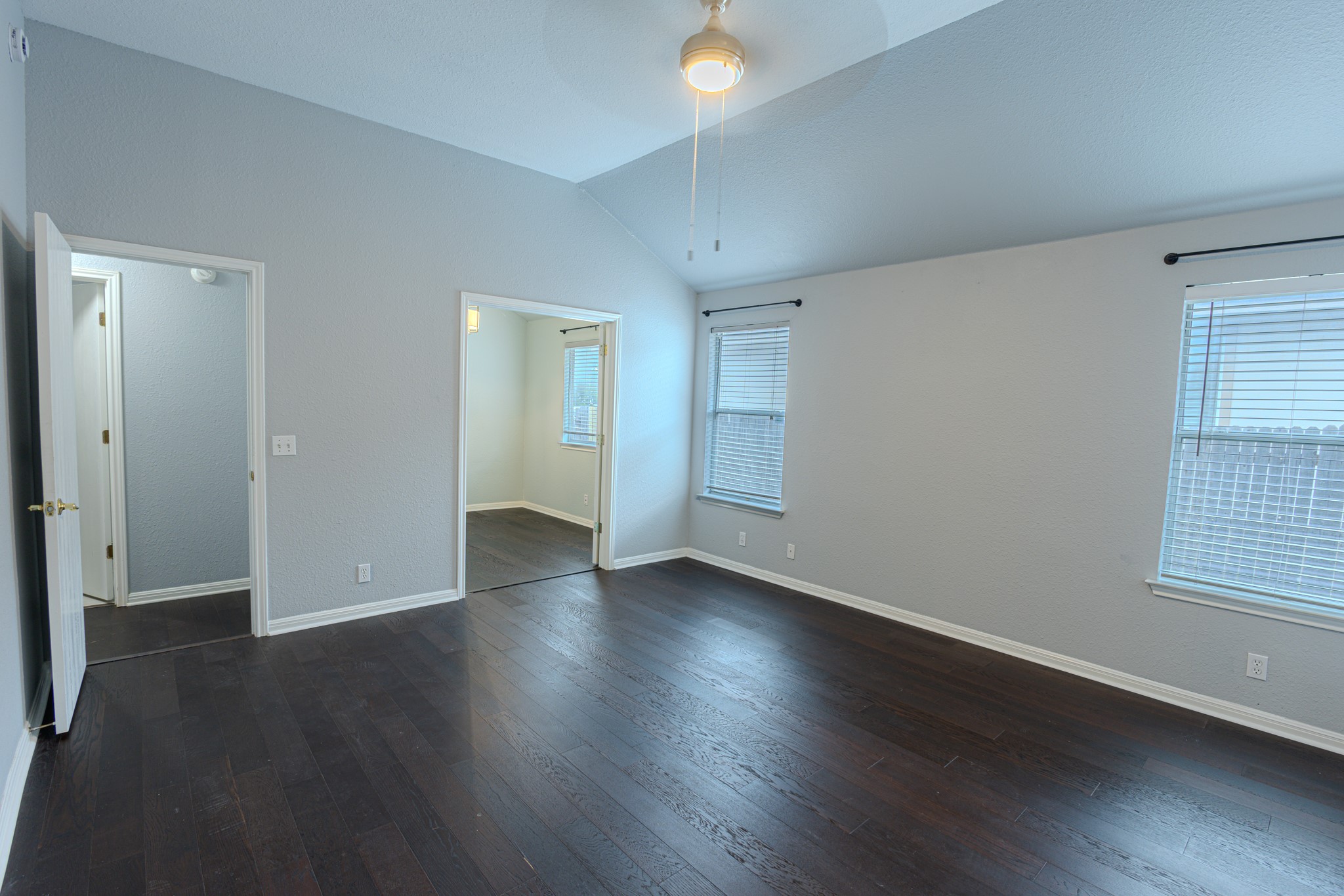 208 Discovery Kyle, TX 78640 - Photo 18 of 31 Spacious room featuring vaulted ceilings, dark wood-finish flooring, and multiple windows with horizontal blinds