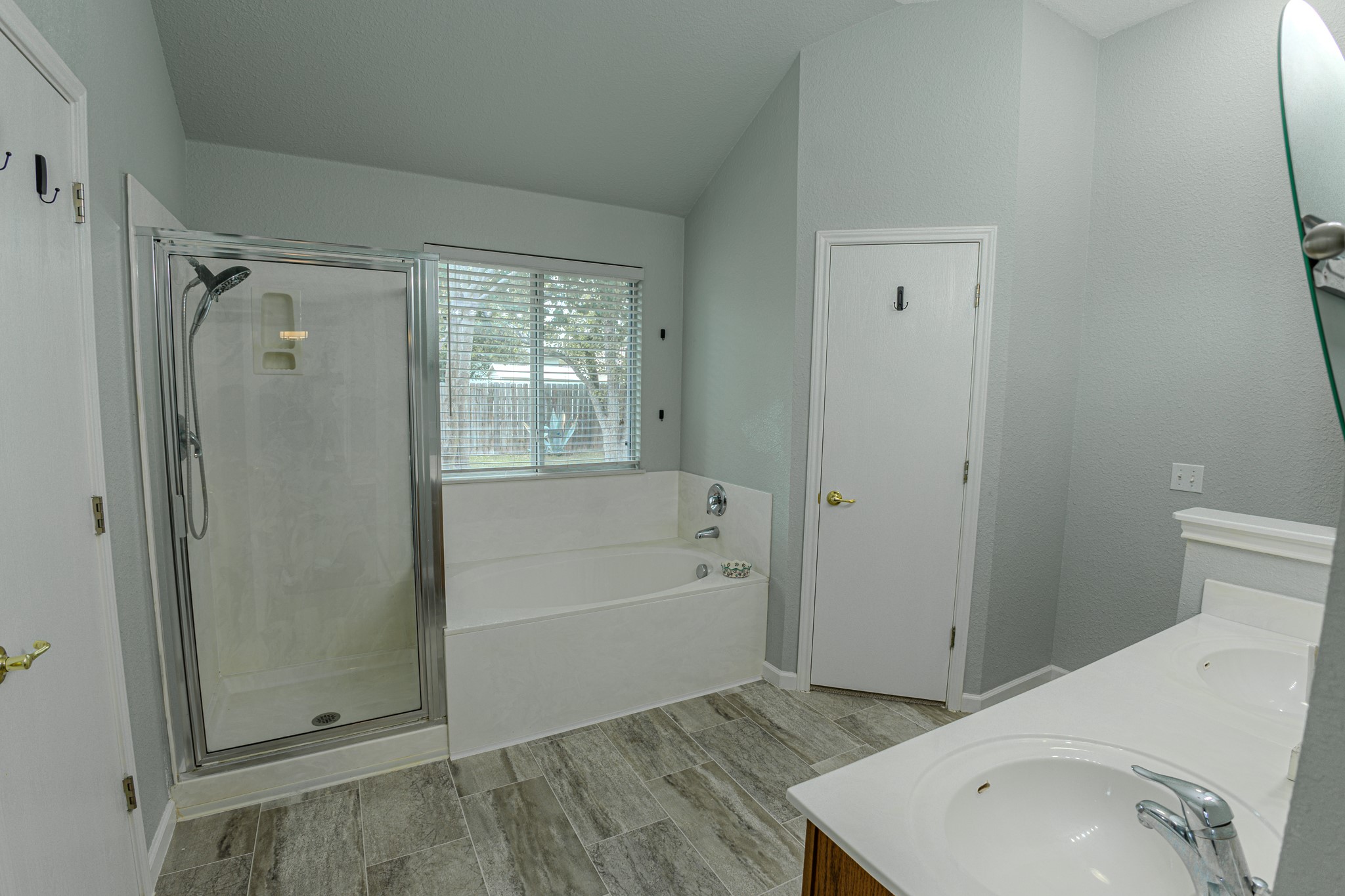 208 Discovery Kyle, TX 78640 - Photo 21 of 31 Bathroom featuring a walk-in shower with glass enclosure, a built-in soaking tub, and dual vanities with integrated sinks