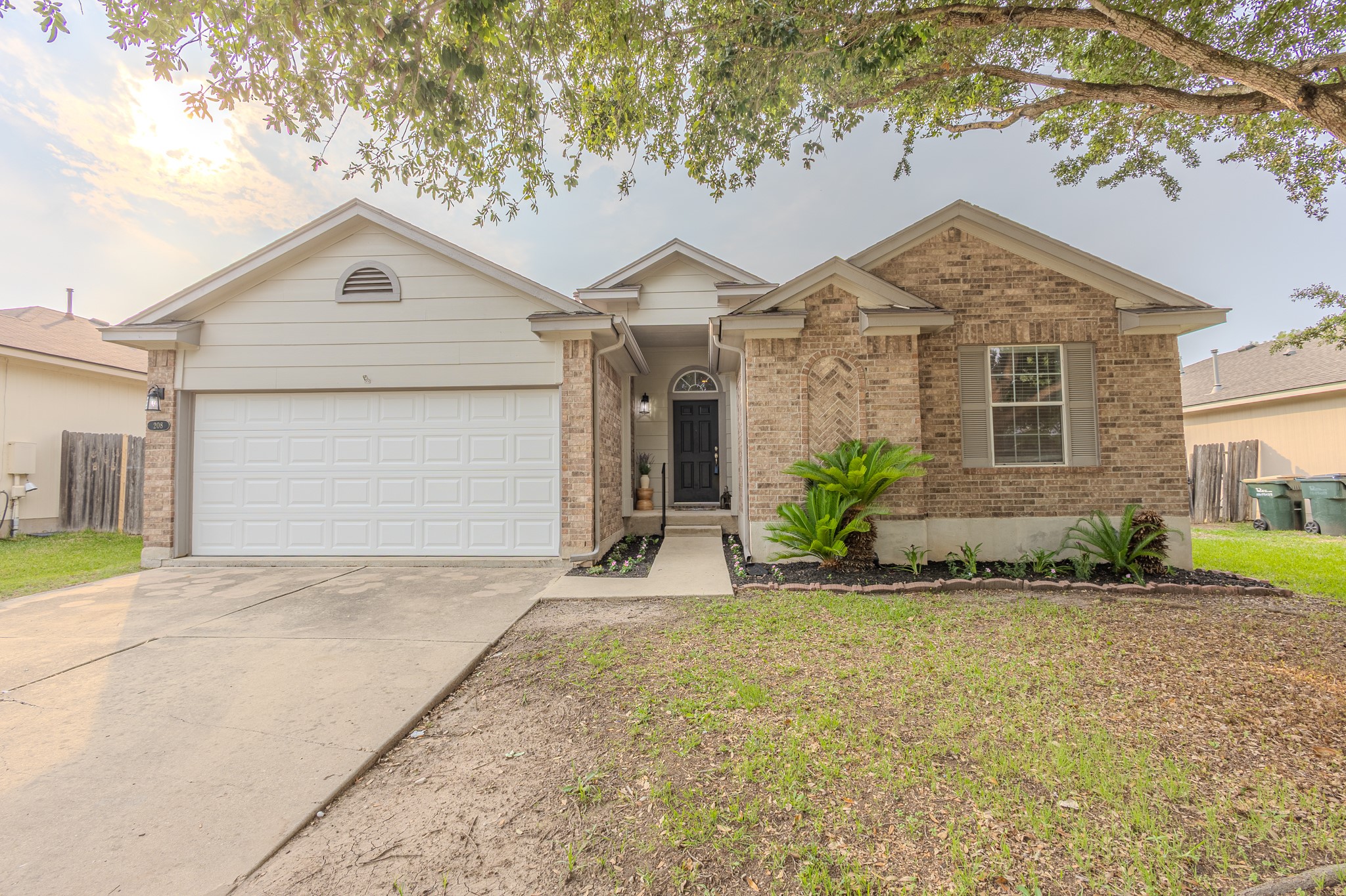208 Discovery Kyle, TX 78640 - Photo 3 of 31 Exterior featuring brick and siding finishes, a two-car garage, established front landscaping, a covered entryway, and a paved driveway
