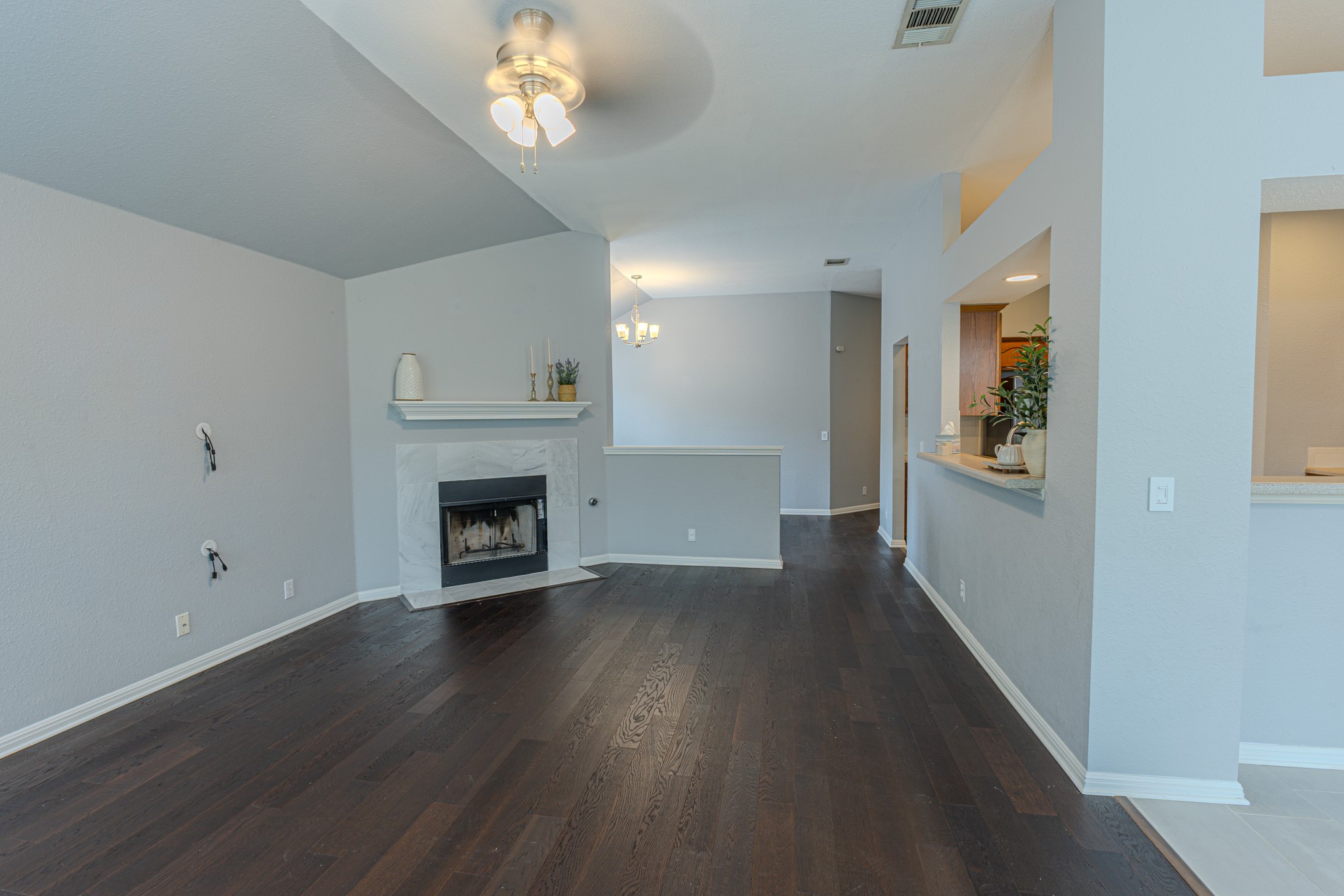 208 Discovery Kyle, TX 78640 - Photo 7 of 31 Spacious living area featuring dark wood-finish flooring, a contemporary fireplace with a light-toned surround and mantel, and vaulted ceilings