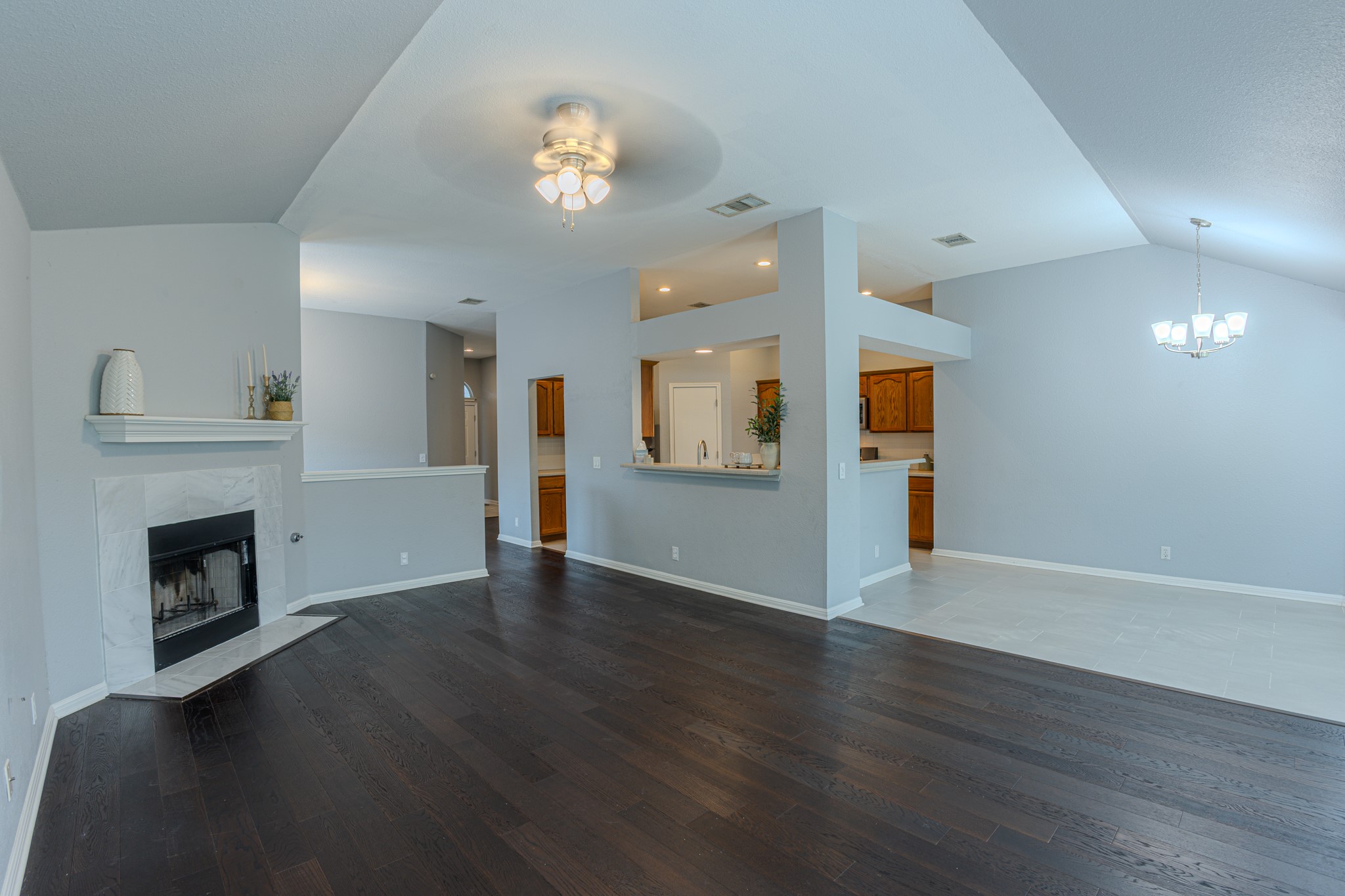 208 Discovery Kyle, TX 78640 - Photo 9 of 31 Spacious interior featuring dark wood-finish flooring, a corner fireplace with a white marble-look surround, and vaulted ceilings