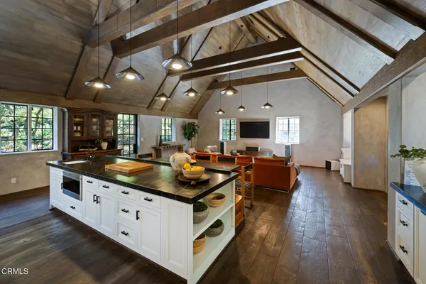 a large kitchen with stainless steel appliances a large counter top a stove a sink and a refrigerator