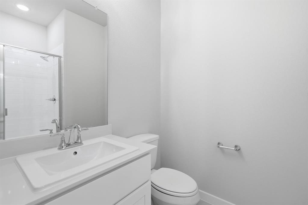 14908 Dust Storm Trail Haslet, TX 76052 - Photo 14 of 20 a bathroom with a white toilet sitting next to a white sink and a mirror