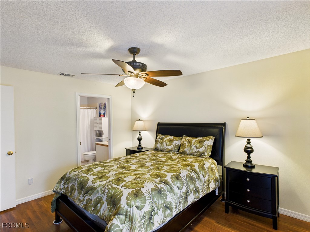 1290 Yesica Ann Circle, Unit G204 Naples, FL 34110 - Photo 15 of 21 a bedroom with a bed and a chandelier