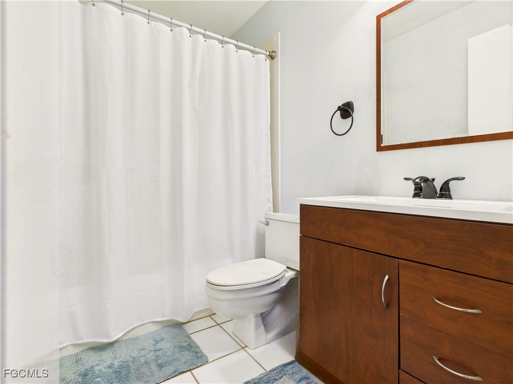 1290 Yesica Ann Circle, Unit G204 Naples, FL 34110 - Photo 7 of 21 a bathroom with a sink a toilet a mirror and shower curtain