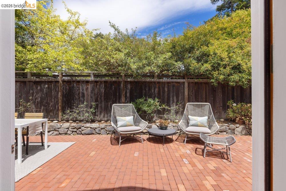 287 Purdue Avenue Kensington, CA 94708 - Photo 32 of 60 Brick paver patio featuring a wooden privacy fence, stone retaining wall, and mature trees