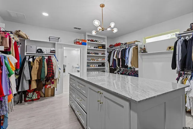 a view of walk in closet with clothes and shoes