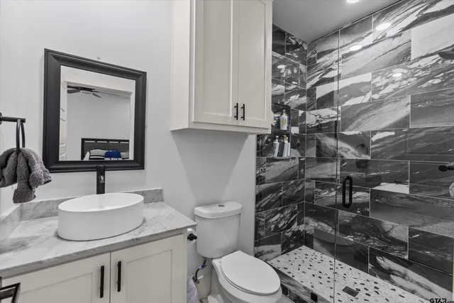 a bathroom with a granite countertop toilet sink and mirror