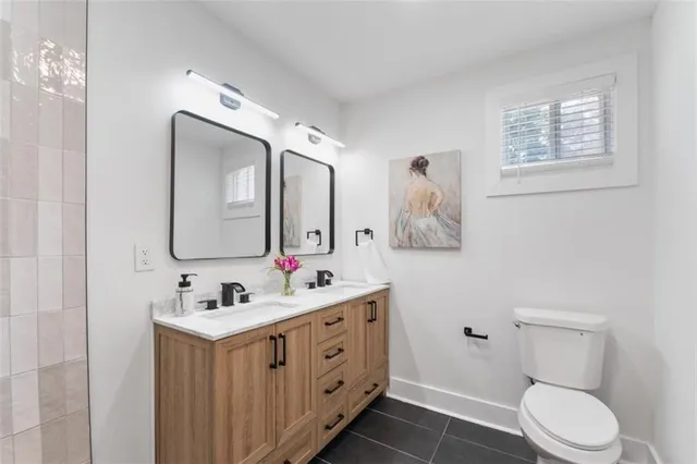 a bathroom with a toilet sink double vanity and mirror