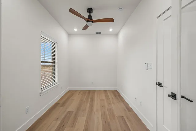a view of a hallway with wooden floor and a window