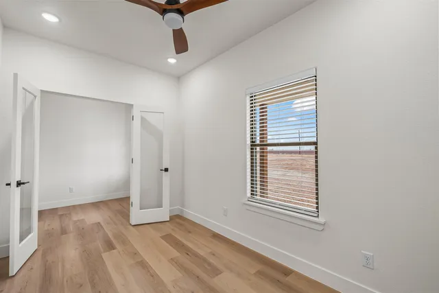 a view of an empty room with a window and wooden floor