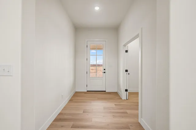 a view of a hallway with wooden floor and a bathroom