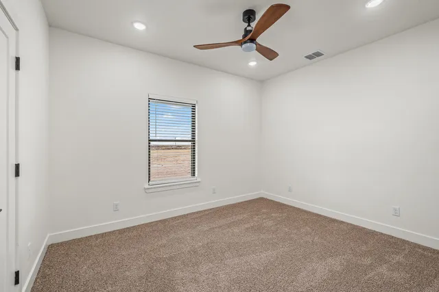 an empty room with a window and a ceiling fan