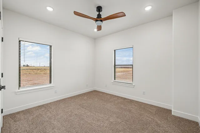 an empty room with a window and a ceiling fan