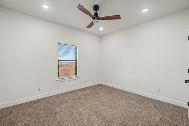 an empty room with a window and a ceiling fan