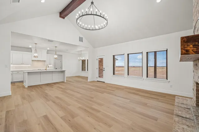 a view of an empty room with a window and kitchen view
