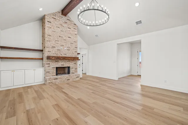 a view of an empty room with wooden floor and fire place
