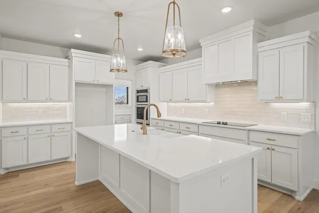 a large white kitchen with a refrigerator a sink dishwasher a oven and a dining table with wooden floor