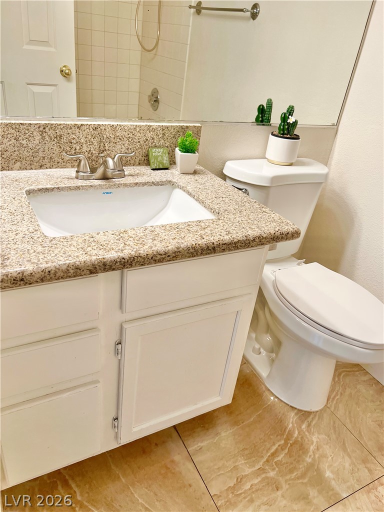9708 Ridge Creek Place Las Vegas, NV 89134 - Photo 17 of 34 Granite counters complement the vanity with a convenient toilet nearby, all set upon elegant tile flooring.