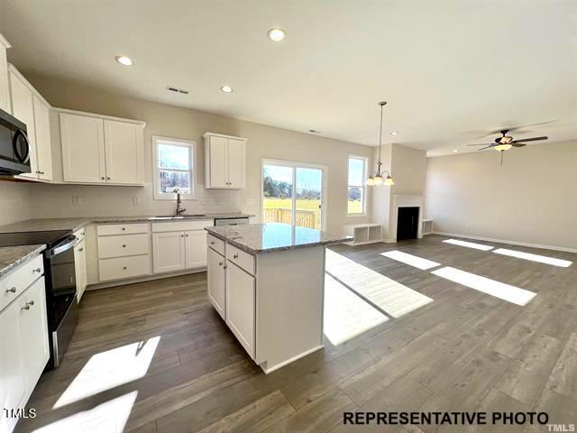 409 Springtooth Drive Zebulon, NC 27597 - Photo 3 of 8 a large kitchen with stainless steel appliances kitchen island granite countertop a stove a sink and white cabinets