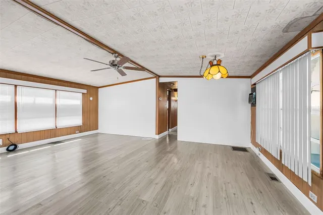a view of empty room with wooden floor and fan