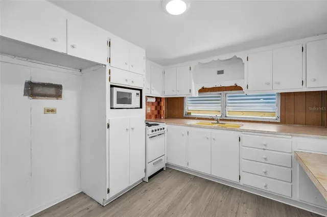a kitchen with cabinets stainless steel appliances and wooden floor