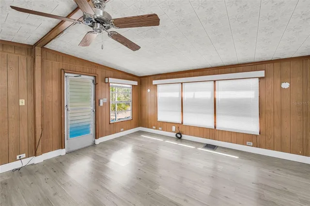 a view of an empty room with a window and wooden floor