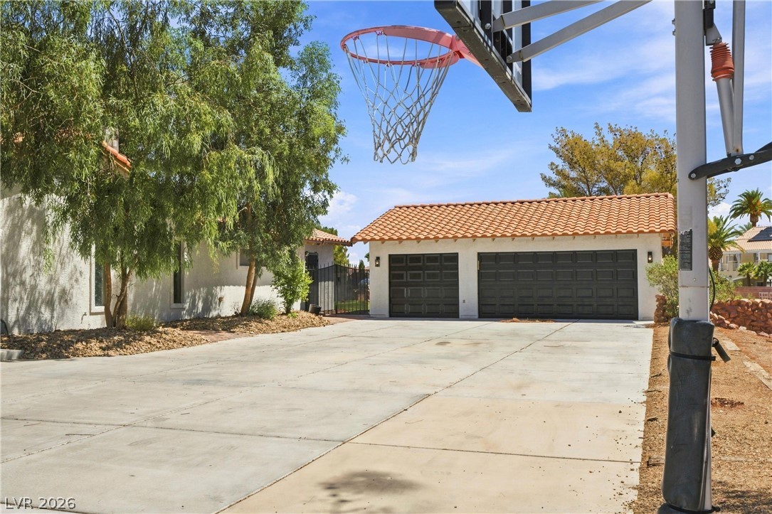 7744 Rancho Destino Road Las Vegas, NV 89123 - Photo 2 of 48 A spacious concrete driveway leads toward a detached garage topped with Spanish tile roofing.