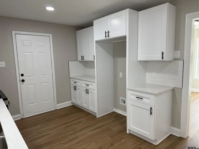 a kitchen with white cabinets and wooden floor