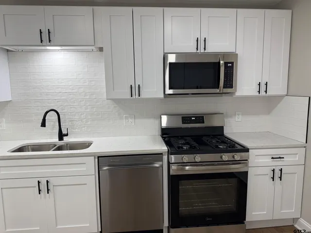 a kitchen with cabinets stainless steel appliances and a sink
