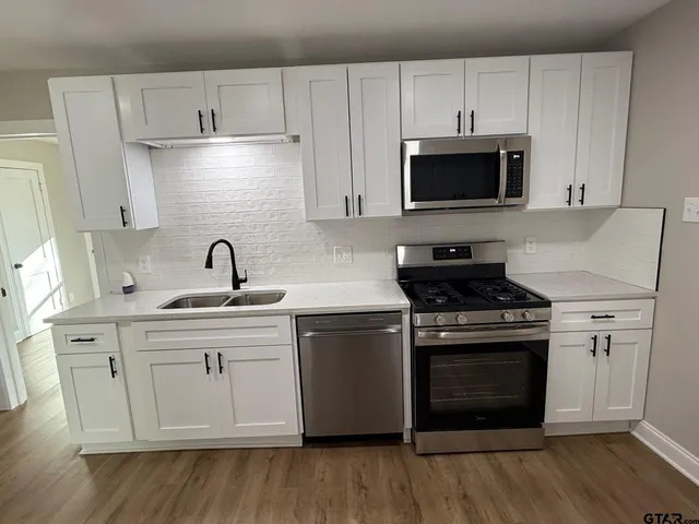 a kitchen with white cabinets and stainless steel appliances