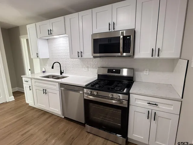 a kitchen with stainless steel appliances granite countertop a sink stove and microwave with wooden floor