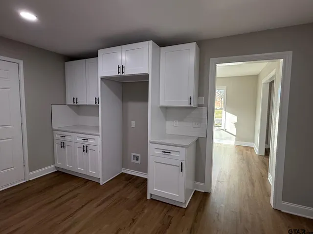 a kitchen with wooden floors and white cabinets
