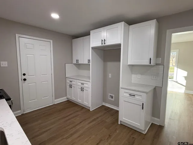 a kitchen with cabinets wooden floor and stainless steel appliances
