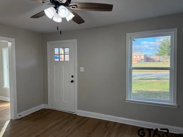 a view of an empty room with wooden floor and a window